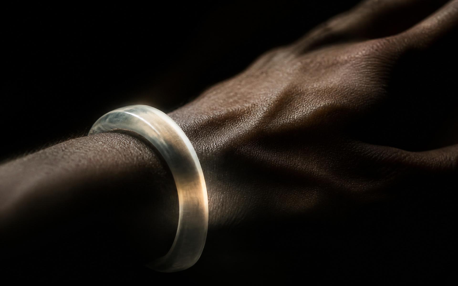 A translucent object catching a narrow plane of light against a dark wrist